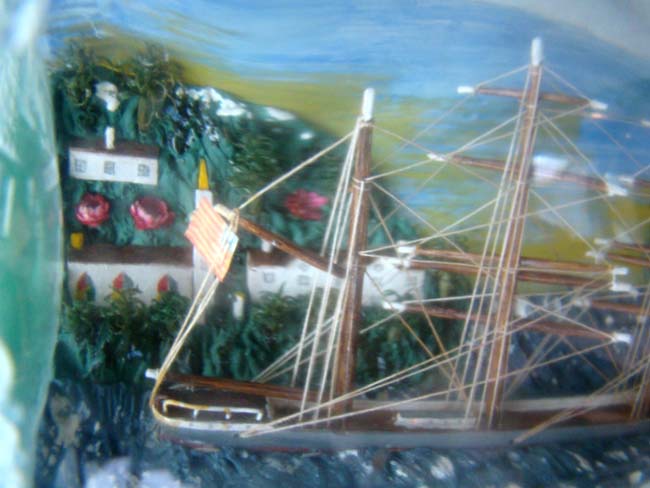 A four masted ship in a bottle flying an American flag with an American coastal town in the background. Circa 1930-1940 — image 2